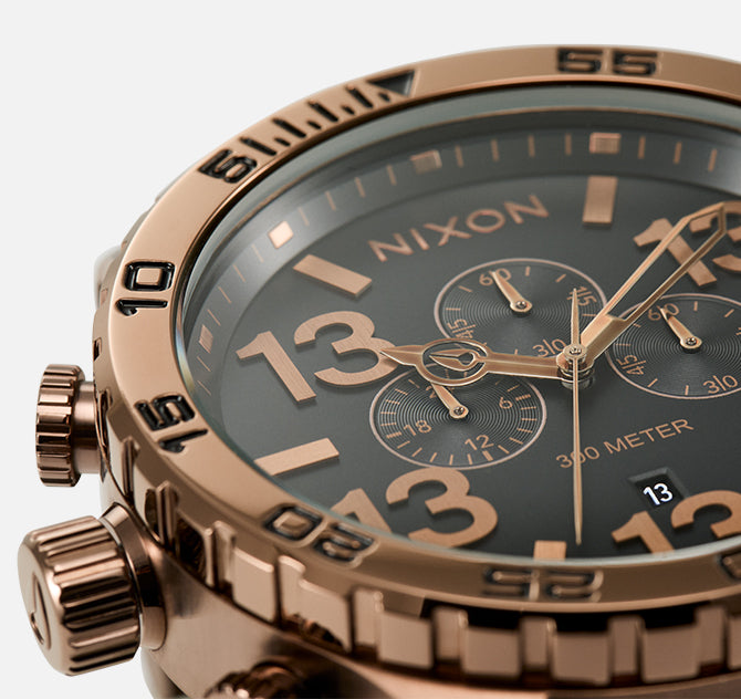 Close-up of a Nixon "Friday the 13th" watch with a dark face, rose gold accents, and the number 13 prominently displayed.