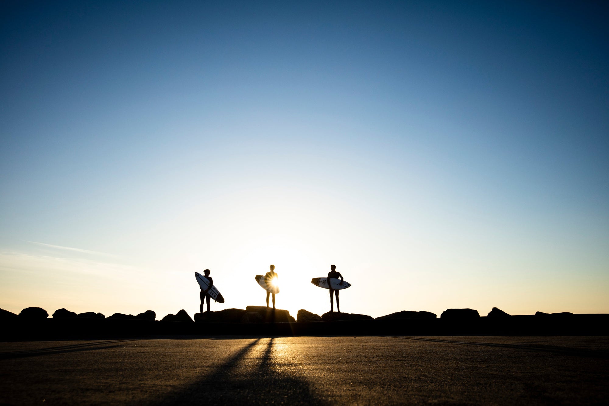 Surfers stand with their boards at the ocean