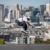 A skateboarder catches air with a city out of focus in the background.